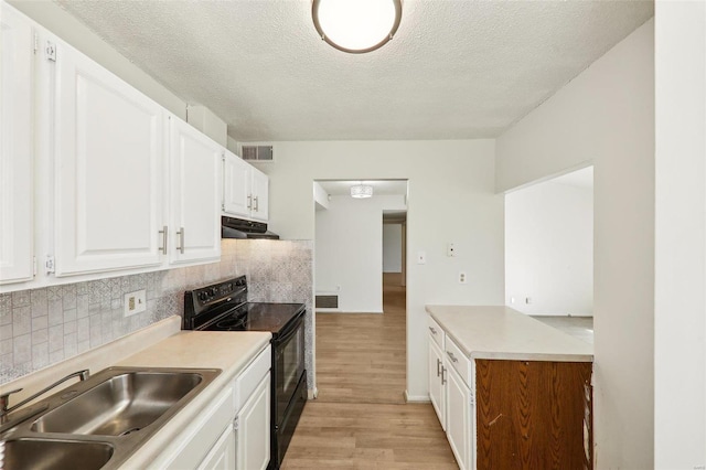 kitchen featuring visible vents, black electric range oven, white cabinetry, a sink, and under cabinet range hood