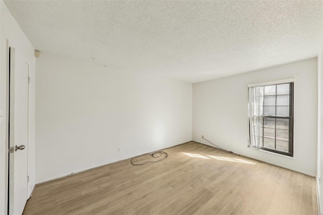 spare room with light wood-type flooring and a textured ceiling