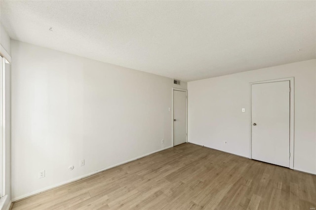 unfurnished bedroom with light wood-style floors, visible vents, and a textured ceiling