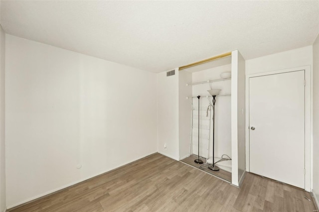 unfurnished bedroom featuring light wood-style floors, visible vents, and a closet