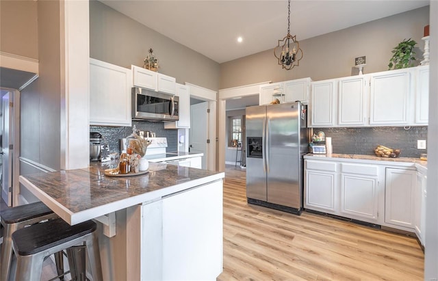 kitchen with appliances with stainless steel finishes, a breakfast bar, and white cabinets