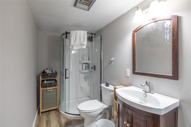 bathroom with hardwood / wood-style flooring, vanity, toilet, and a shower with door