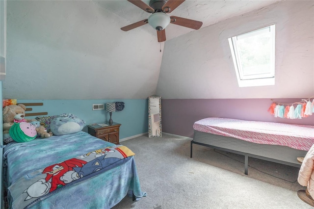 carpeted bedroom with ceiling fan and vaulted ceiling with skylight