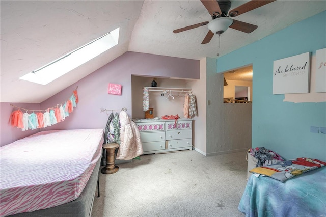 carpeted bedroom with ceiling fan, vaulted ceiling with skylight, and a textured ceiling