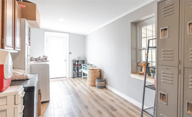 interior space featuring light hardwood / wood-style floors, ornamental molding, cabinets, and washing machine and clothes dryer