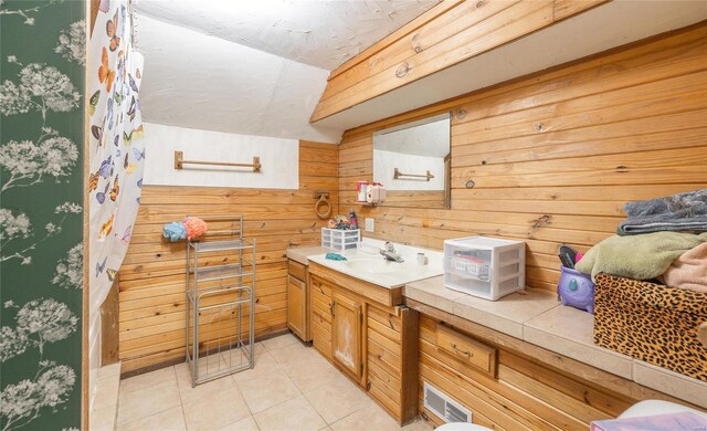 bathroom featuring tile patterned flooring, vanity, and wood walls