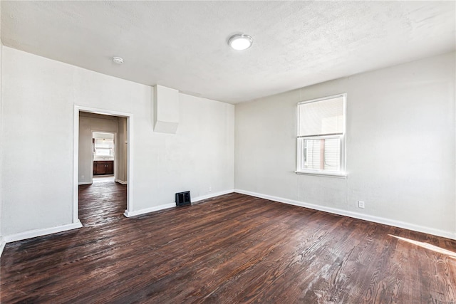 spare room featuring dark wood-type flooring and a textured ceiling