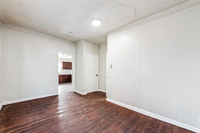 unfurnished room featuring dark wood-type flooring, wood walls, and a textured ceiling