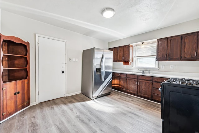 kitchen featuring stainless steel refrigerator with ice dispenser, dark brown cabinets, sink, black range, and light hardwood / wood-style floors