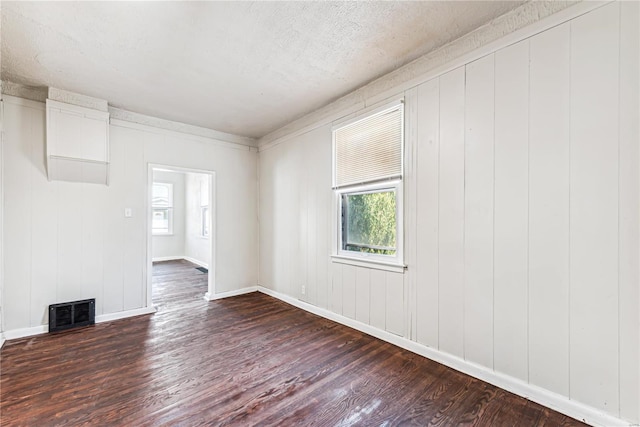 spare room featuring wooden walls, a textured ceiling, and dark hardwood / wood-style flooring