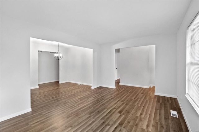 empty room with a chandelier and dark hardwood / wood-style flooring