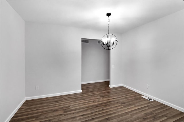 empty room featuring an inviting chandelier and dark hardwood / wood-style floors