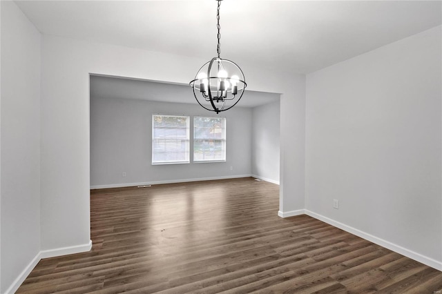 unfurnished dining area featuring a notable chandelier and dark hardwood / wood-style flooring