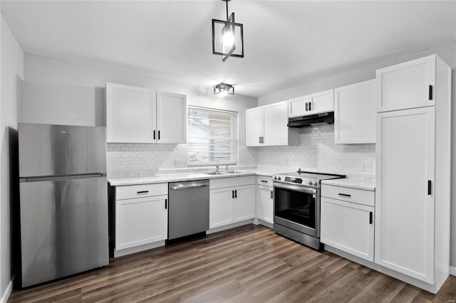 kitchen featuring tasteful backsplash, appliances with stainless steel finishes, decorative light fixtures, white cabinets, and dark wood-type flooring