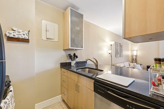 kitchen featuring sink, light tile patterned floors, stainless steel dishwasher, light brown cabinets, and dark stone countertops