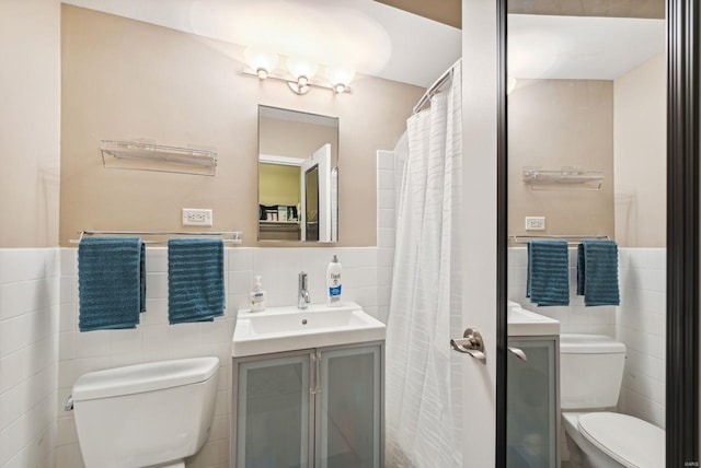 bathroom with tile walls, vanity, and toilet