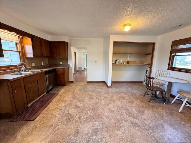 kitchen featuring stainless steel dishwasher, a healthy amount of sunlight, tasteful backsplash, and a sink