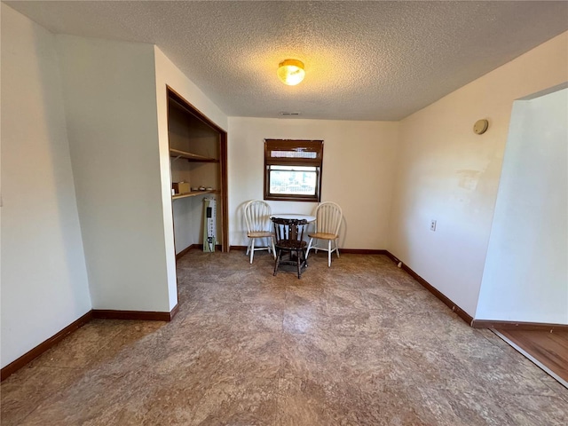 dining area with carpet floors, a textured ceiling, and baseboards