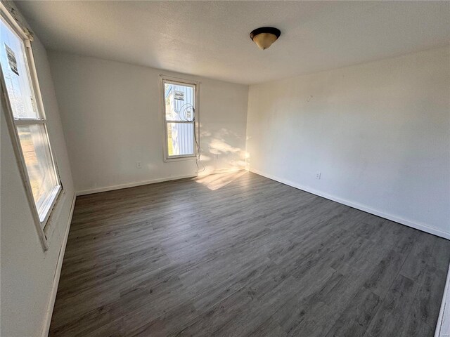 empty room featuring baseboards, dark wood-style floors, and a textured ceiling