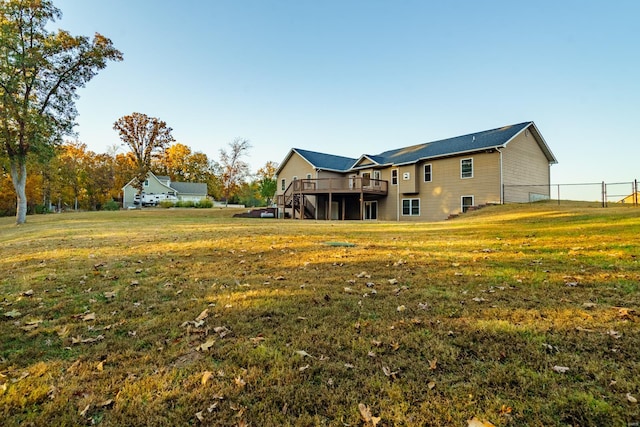 rear view of property featuring a wooden deck and a lawn