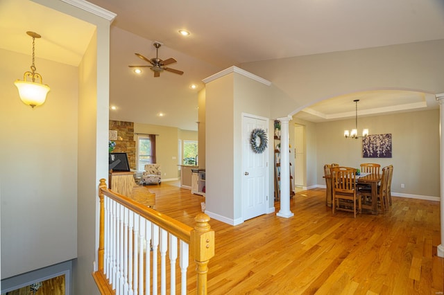 interior space with a tray ceiling, vaulted ceiling, decorative columns, light hardwood / wood-style floors, and a notable chandelier