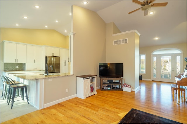 kitchen featuring light hardwood / wood-style floors, lofted ceiling, white cabinets, and stainless steel fridge with ice dispenser