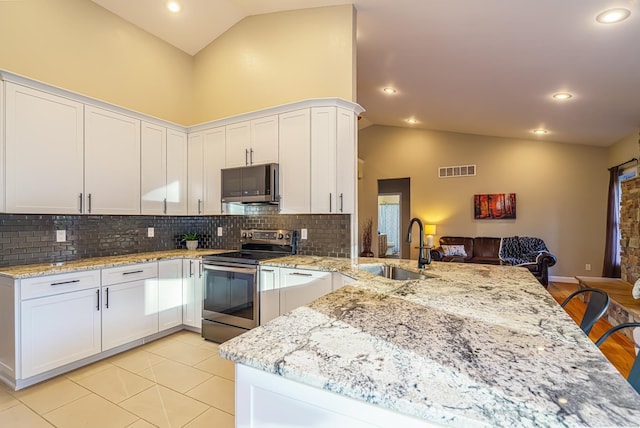 kitchen with sink, a kitchen breakfast bar, white cabinets, and stainless steel appliances