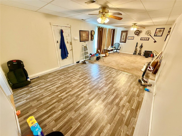 workout area featuring ceiling fan, a drop ceiling, and hardwood / wood-style floors