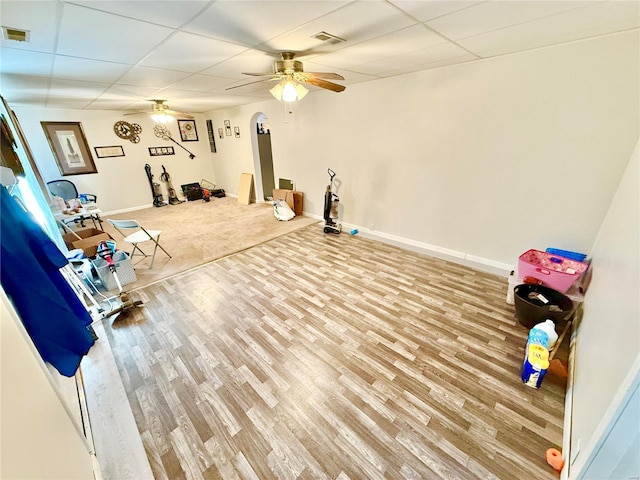 exercise area with ceiling fan, a paneled ceiling, and hardwood / wood-style floors