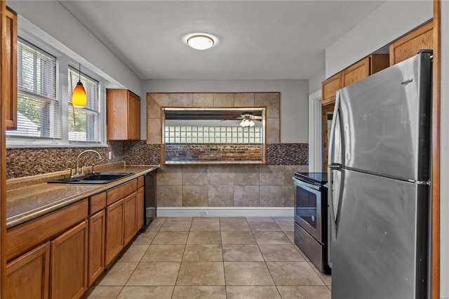 kitchen featuring appliances with stainless steel finishes, sink, light tile patterned floors, and ceiling fan