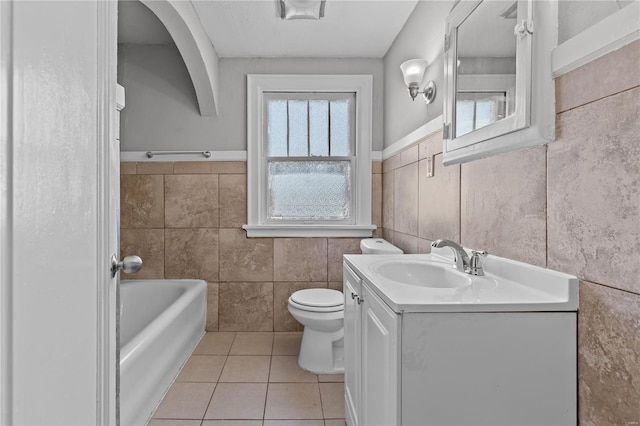 bathroom featuring toilet, tile walls, vanity, a bathtub, and tile patterned flooring