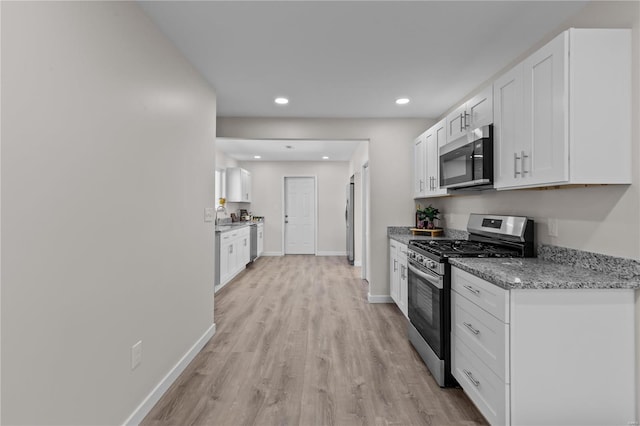 kitchen featuring light stone countertops, sink, appliances with stainless steel finishes, white cabinets, and light hardwood / wood-style flooring