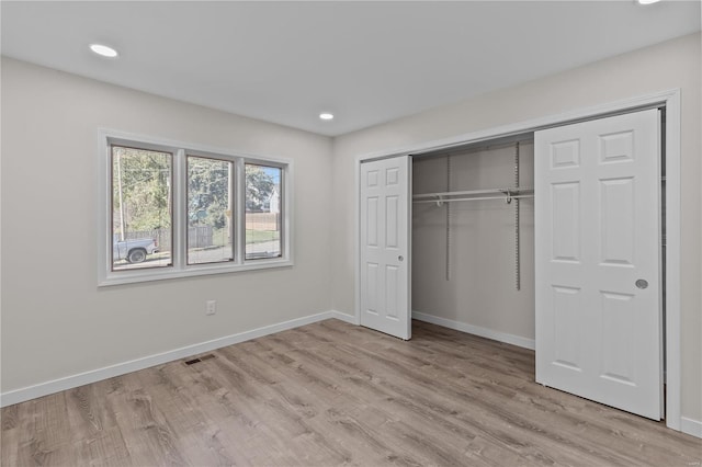 unfurnished bedroom with a closet and light hardwood / wood-style floors