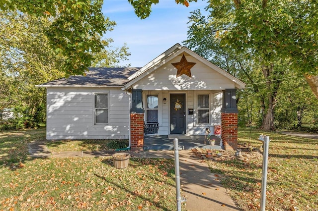 bungalow-style home with a front yard, covered porch, and brick siding