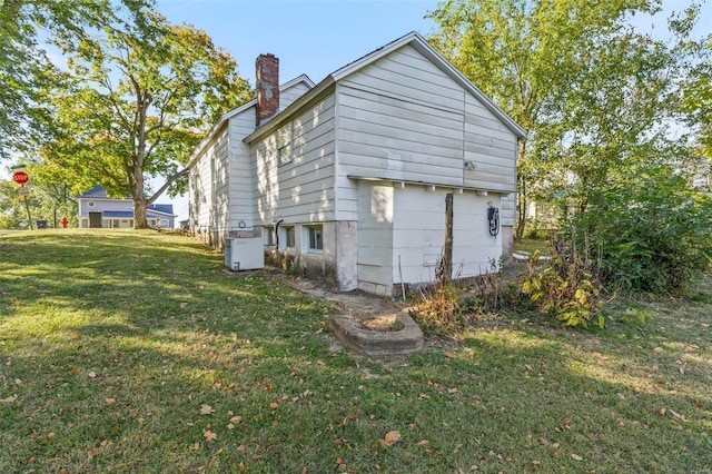 back of house featuring a lawn and a chimney