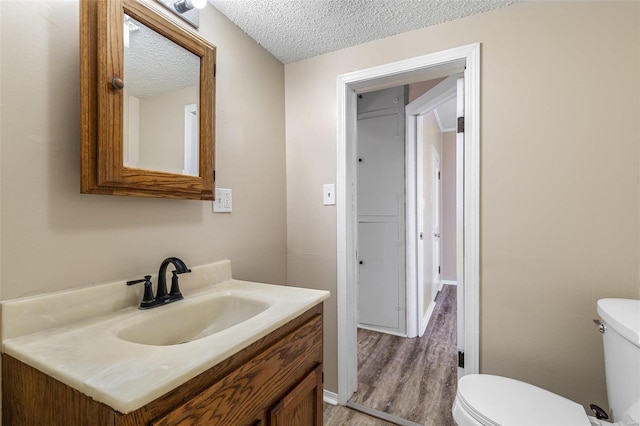 bathroom with toilet, wood finished floors, a textured ceiling, and vanity