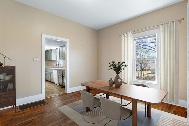 dining space featuring light wood-type flooring, visible vents, and baseboards