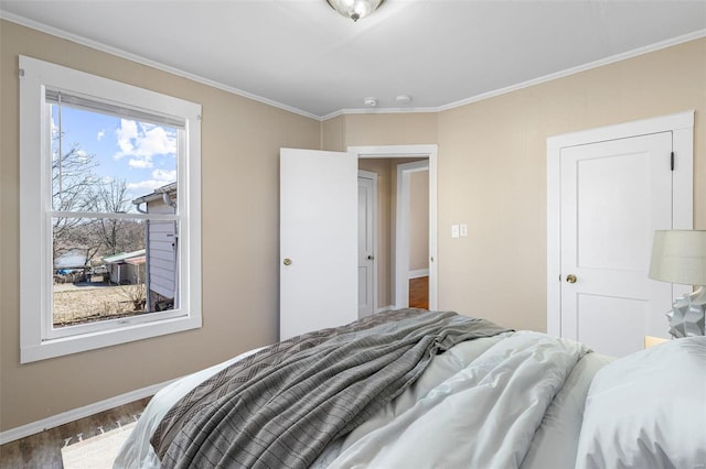 bedroom with crown molding, baseboards, and wood finished floors