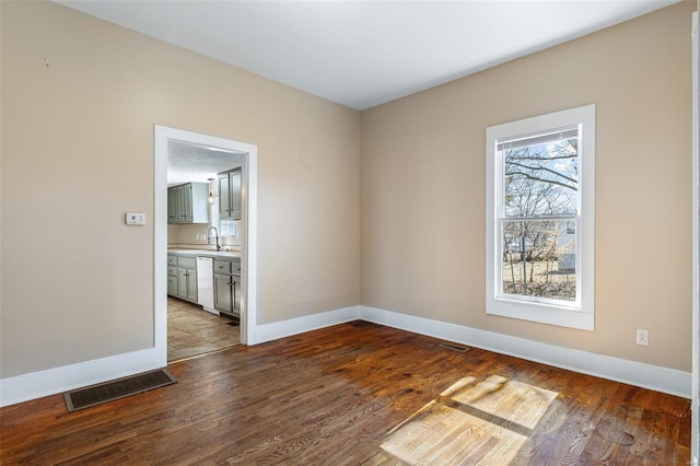 empty room featuring visible vents, a sink, and wood finished floors