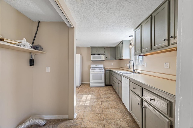 kitchen featuring white appliances, light countertops, a textured ceiling, gray cabinetry, and a sink