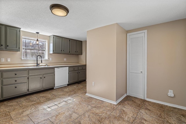 kitchen featuring baseboards, dishwasher, light countertops, gray cabinetry, and a sink