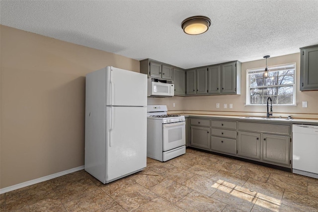 kitchen featuring white appliances, baseboards, a sink, and gray cabinetry