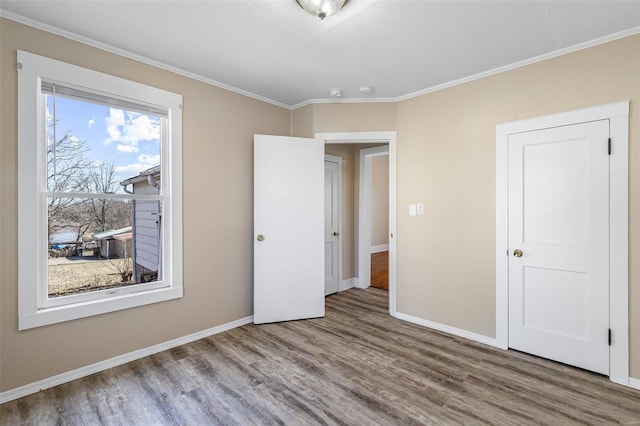 unfurnished bedroom with crown molding, baseboards, and wood finished floors