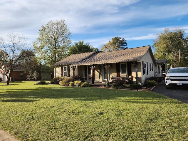 ranch-style home featuring covered porch and a front lawn