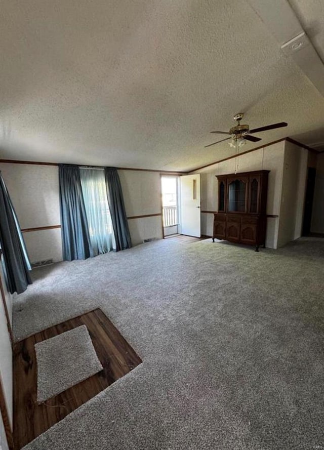 unfurnished living room with carpet, a textured ceiling, and ceiling fan