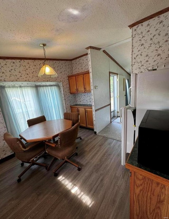 dining room with ornamental molding, a textured ceiling, dark wood-type flooring, and vaulted ceiling