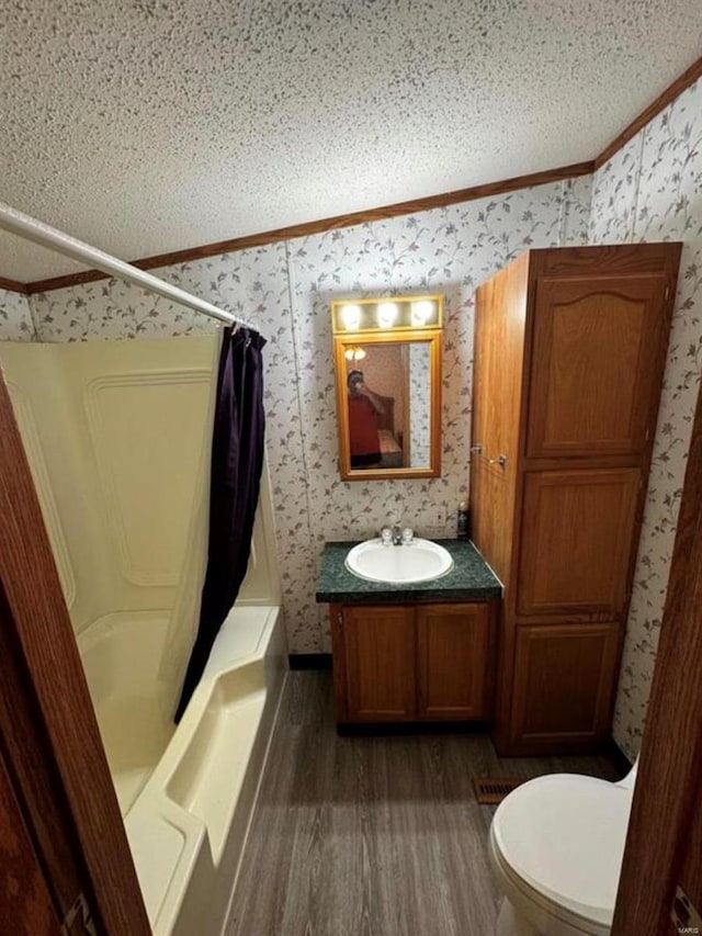 full bathroom featuring a textured ceiling, toilet, shower / bath combo with shower curtain, vanity, and hardwood / wood-style flooring