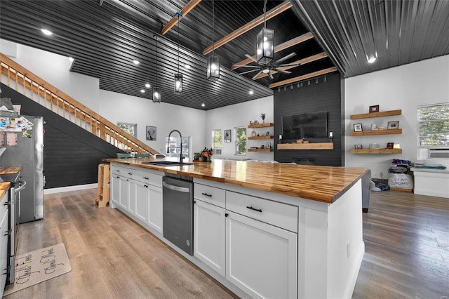 kitchen featuring white cabinetry, butcher block countertops, sink, and a high ceiling