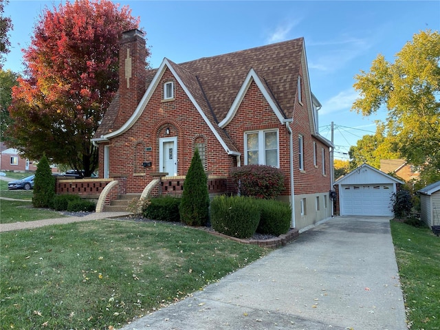 english style home with a garage, a front lawn, and an outbuilding