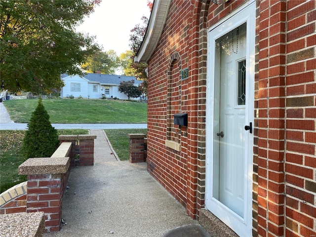 view of exterior entry featuring a lawn